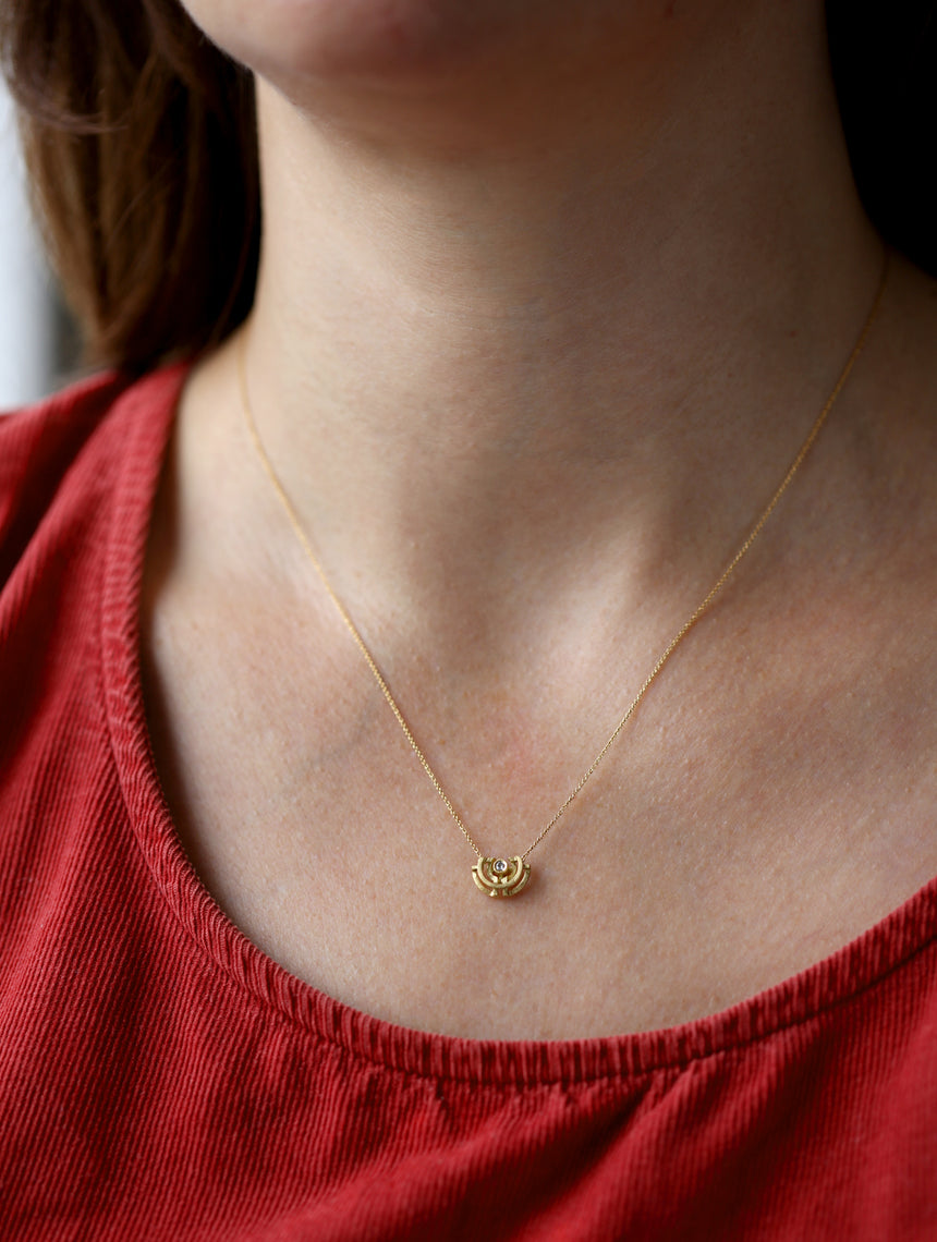 Geometric pendant with semicircle detail, set with a white diamond. 18ct yellow gold, textured finish. Worn around the neck.