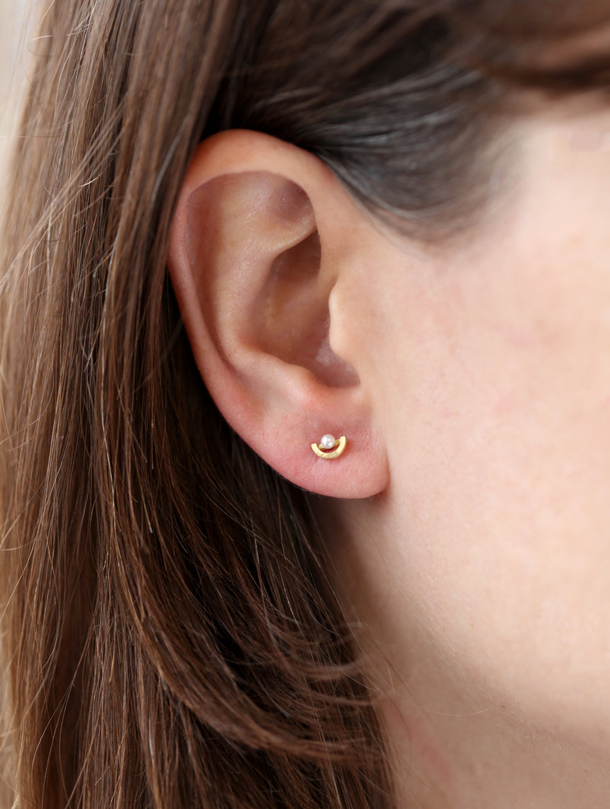 Ear studs with white pearls and semi circle detail. 18ct yellow gold, textured finish. Worn in ear.