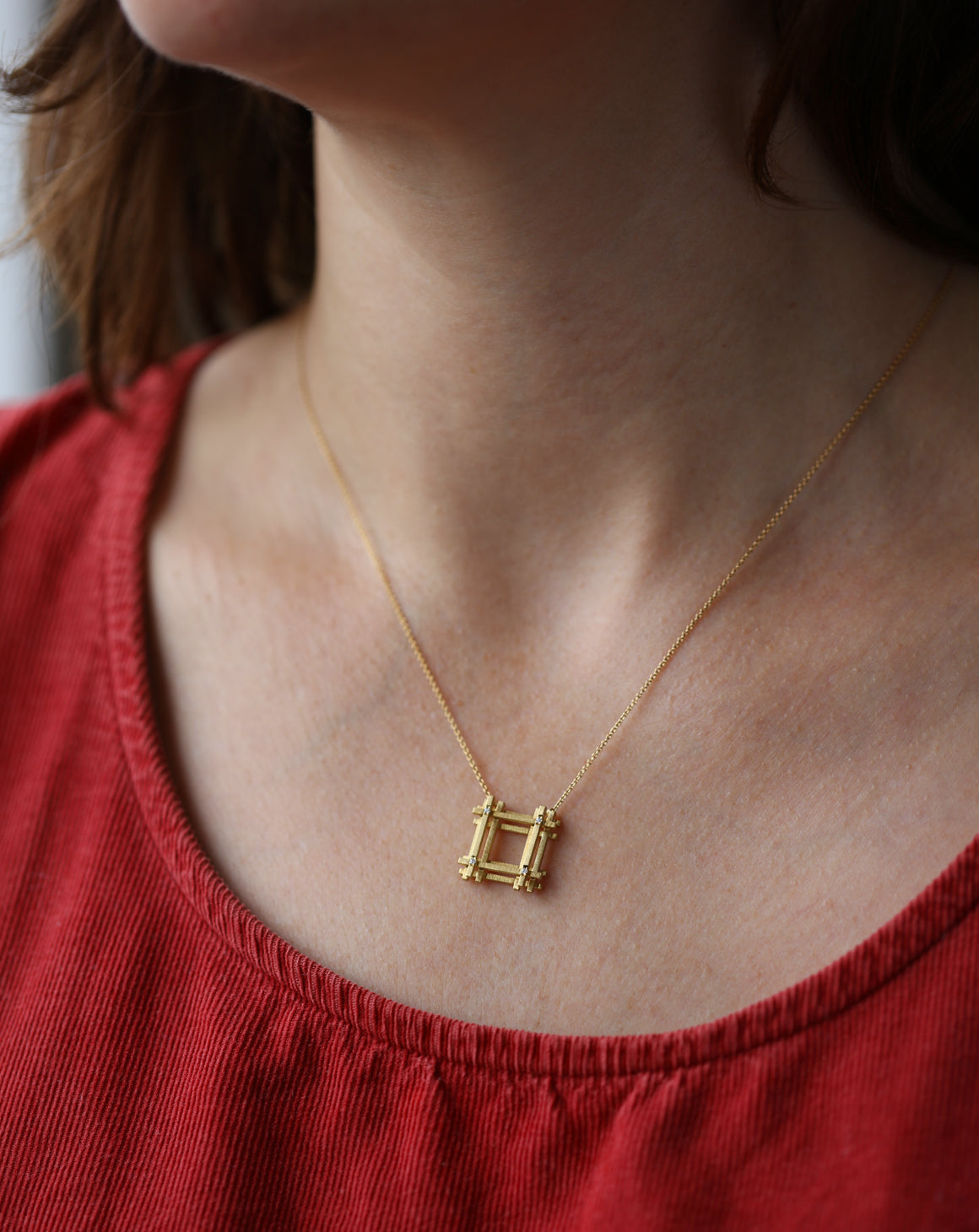 Geometric pendant with square structure detail and four tiny diamonds. 18ct yellow gold textured finish. On neck.