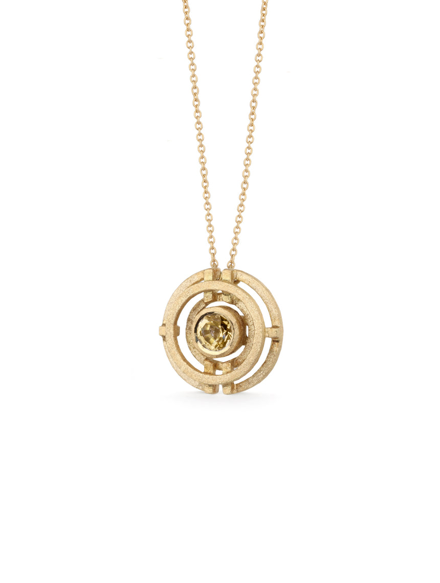 Geometric pendant with concentric circles surrounding yellow sapphire. 18ct yellow gold, textured finish. Side detail.